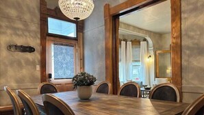 A dining room with a large wooden table, six chairs, and a potted plant. - Epic 8BR Milwaukee Victorian House (Milwaukee)