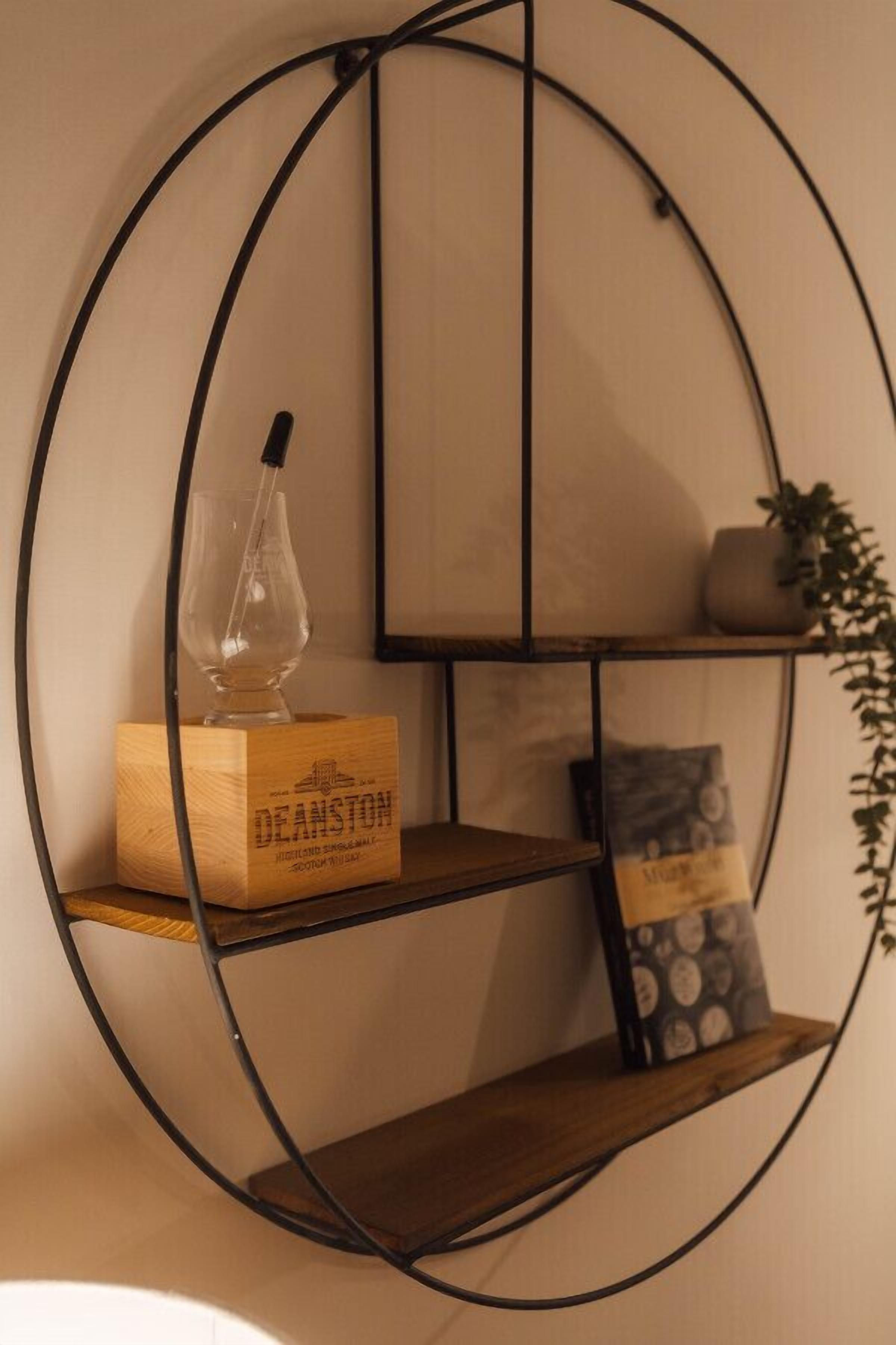 A wall-mounted circular shelf with a wooden box labeled "DEANSTON" and a glass bottle.