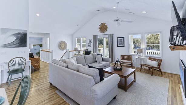 A spacious living room with a large sectional sofa, a dining table, and a ceiling fan. - Corolla vacation rental in a gated golf course community, with beach trolley! (Corolla)