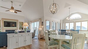 A spacious living area with a dining table, chairs, a sofa, and a TV. - Oceanside vacation rental steps away from the beach access in Corolla, NC! (Corolla)
