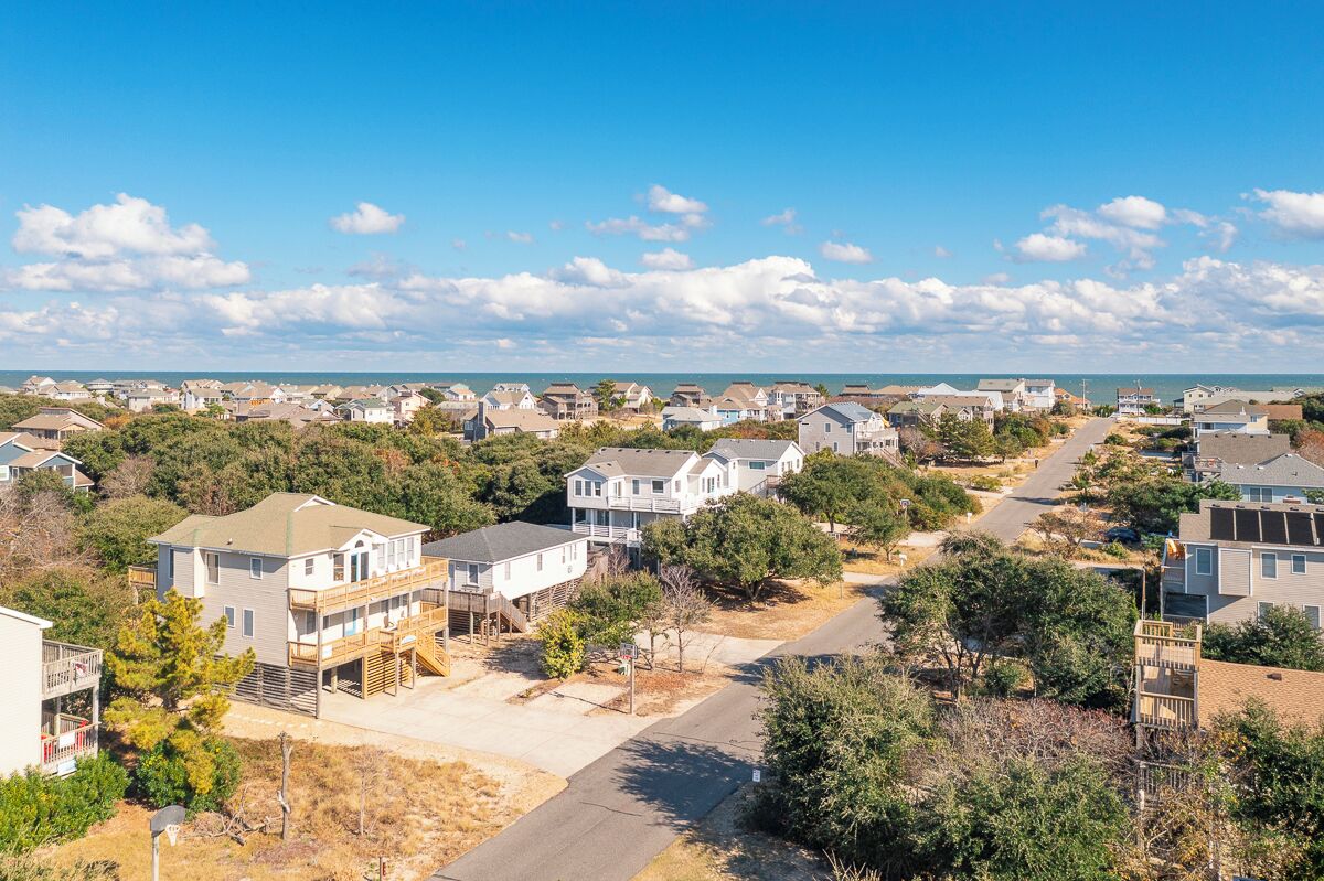 A residential area with houses, a clear sky, and a distant view of the ocean.
