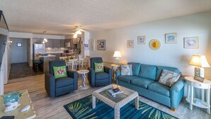 A modern living room with a sofa, armchairs, and a coffee table. There is a kitchen in the background. - Beautiful sunrise views from this oceanfront condo in Kill Devil Hills NC! (Kill Devil Hills)