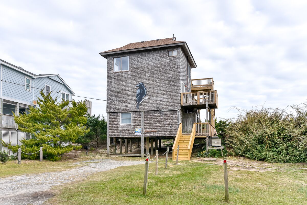 A rustic wooden tower with a bird mural, a wooden deck, and a gravel path leading to it.