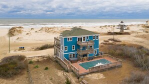 A multi-story beach house with a balcony, a deck, and a view of the ocean.