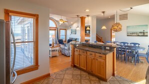 A spacious kitchen with a large island, wooden cabinets, and a dining area with blue chairs.