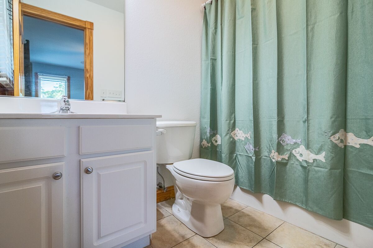 Ein Badezimmer mit Toilette, Waschbecken und einer Duschvorhang mit Fischmuster.
