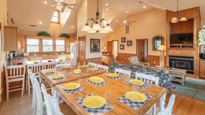 A spacious dining area with a long wooden table set for a meal, surrounded by white chairs. - Pet friendly Hatteras Island home with private pool, hot tub, and sound views (Avon)