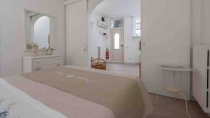 Een slaapkamer met een bed, een kaptafel, een spiegel en een klein tafeltje.