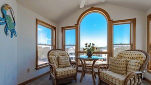 Un solárium con mobiliario de mimbre, ventanas amplias y vistas al paisaje.