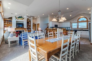 Una cocina amplia con armarios blancos, un comedor con mesa y sillas de madera, y un ventilador de techo.