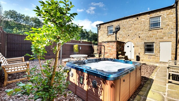 A stone building with a wooden deck, a hot tub, and a wooden fence. - The Old Milking Parlour - 6 bedroom property with hot tub (Oakerthorpe)