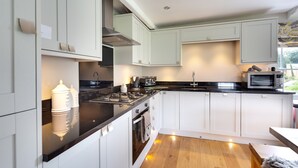 A modern kitchen with white cabinets, a black countertop, and a wooden floor. - The Old Milking Parlour - 6 bedroom property with hot tub (Oakerthorpe)