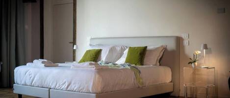 Una habitación de hotel moderna con una cama grande, una mesita de noche con lámpara y una puerta con cerradura electrónica.