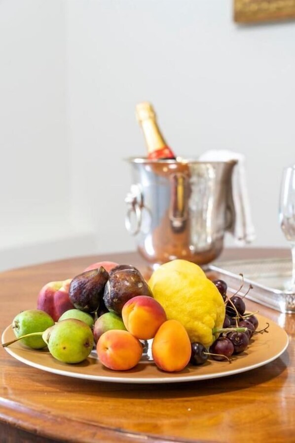 Una bandeja de frutas con diversas frutas y una botella de champán sobre una mesa.