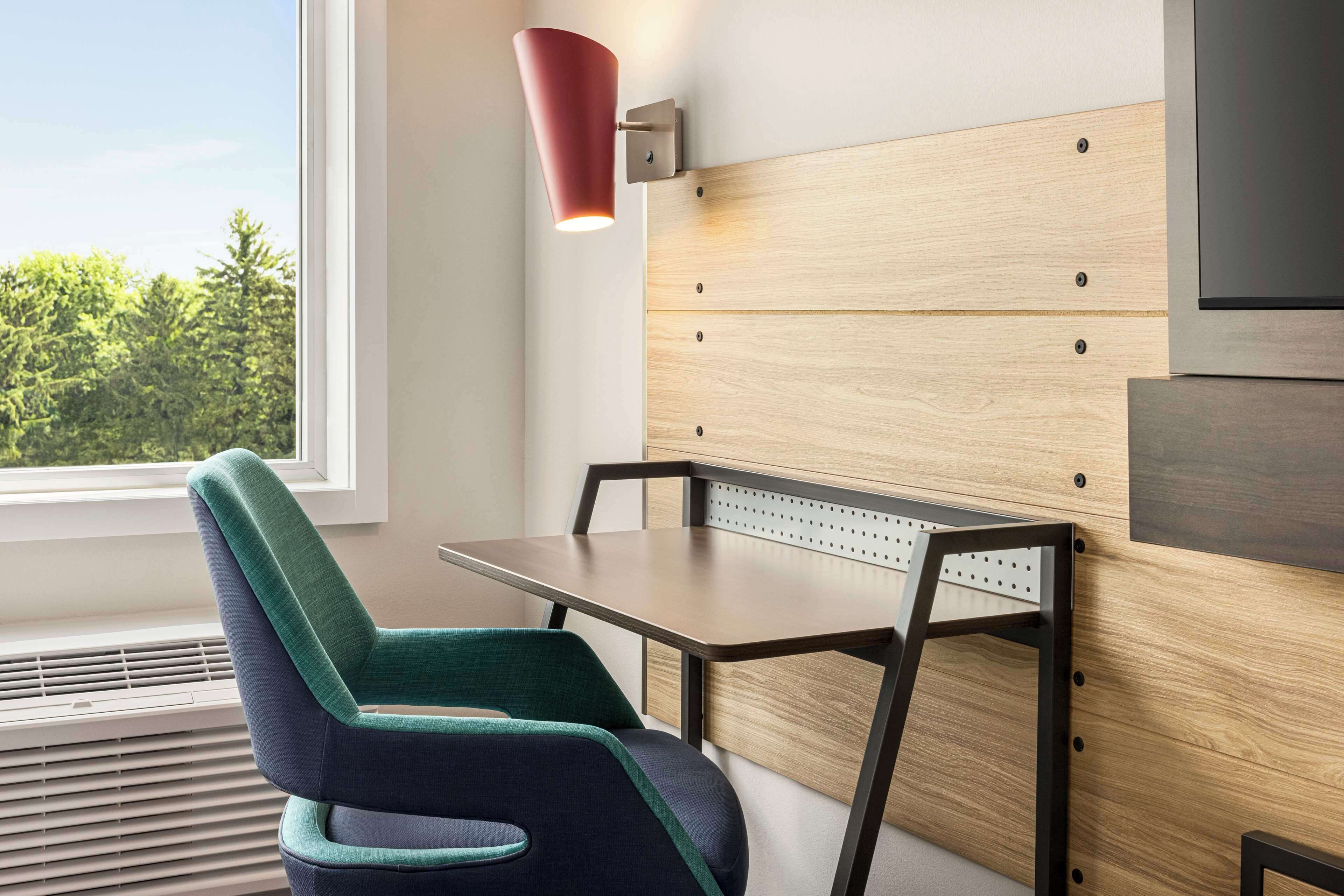 A modern room with a wooden headboard, a table, and a chair.