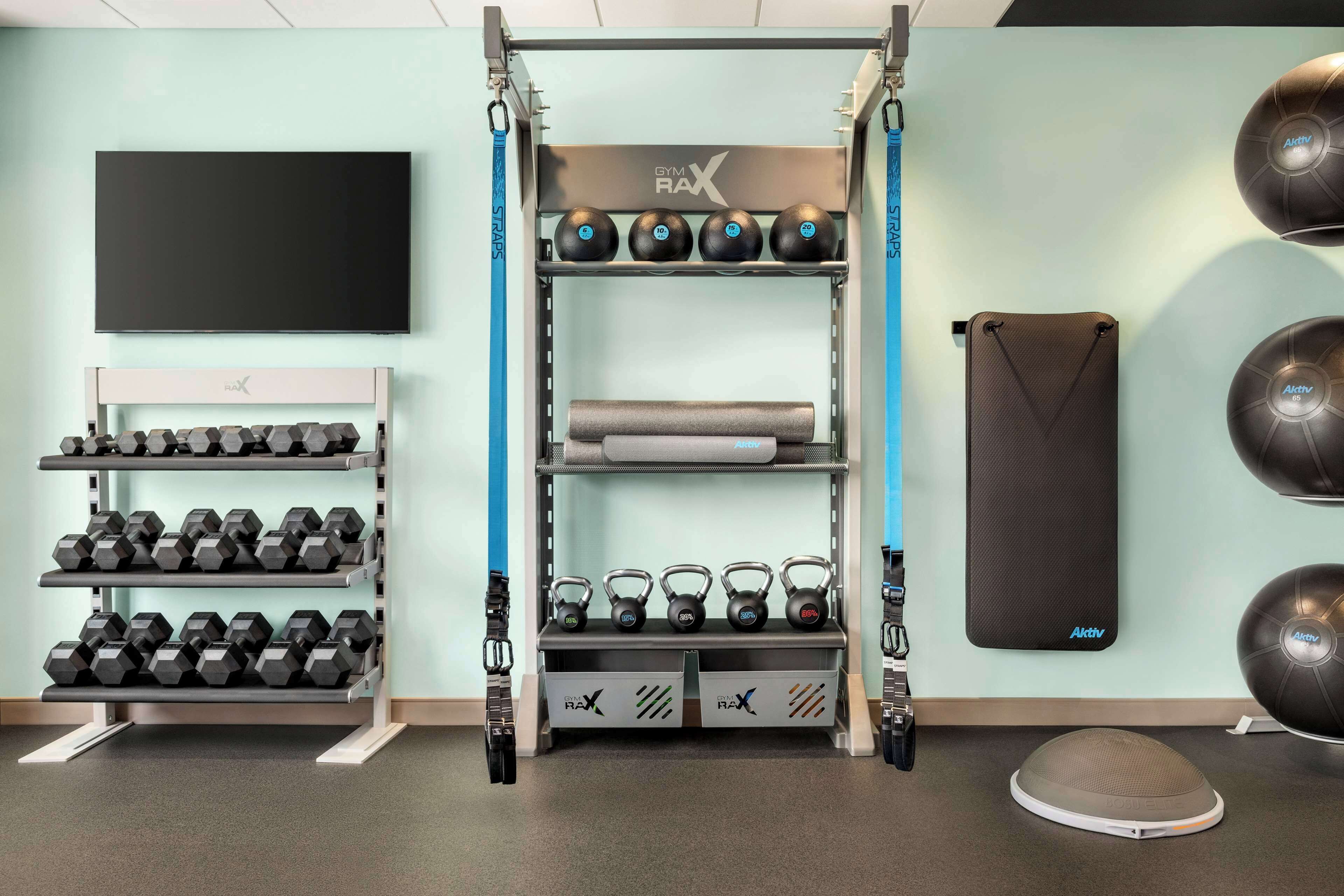 Un gimnasio con pesas, mancuernas y pelotas de ejercicio.