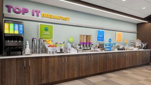 Un área de desayuno con un letrero que dice "TOP IT BREAKFAST" y varios dispensadores de comida y bebida.