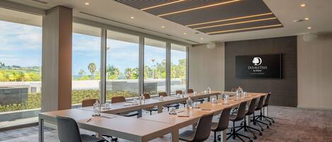 A conference room with a long table, chairs, and a TV displaying the DoubleTree logo.