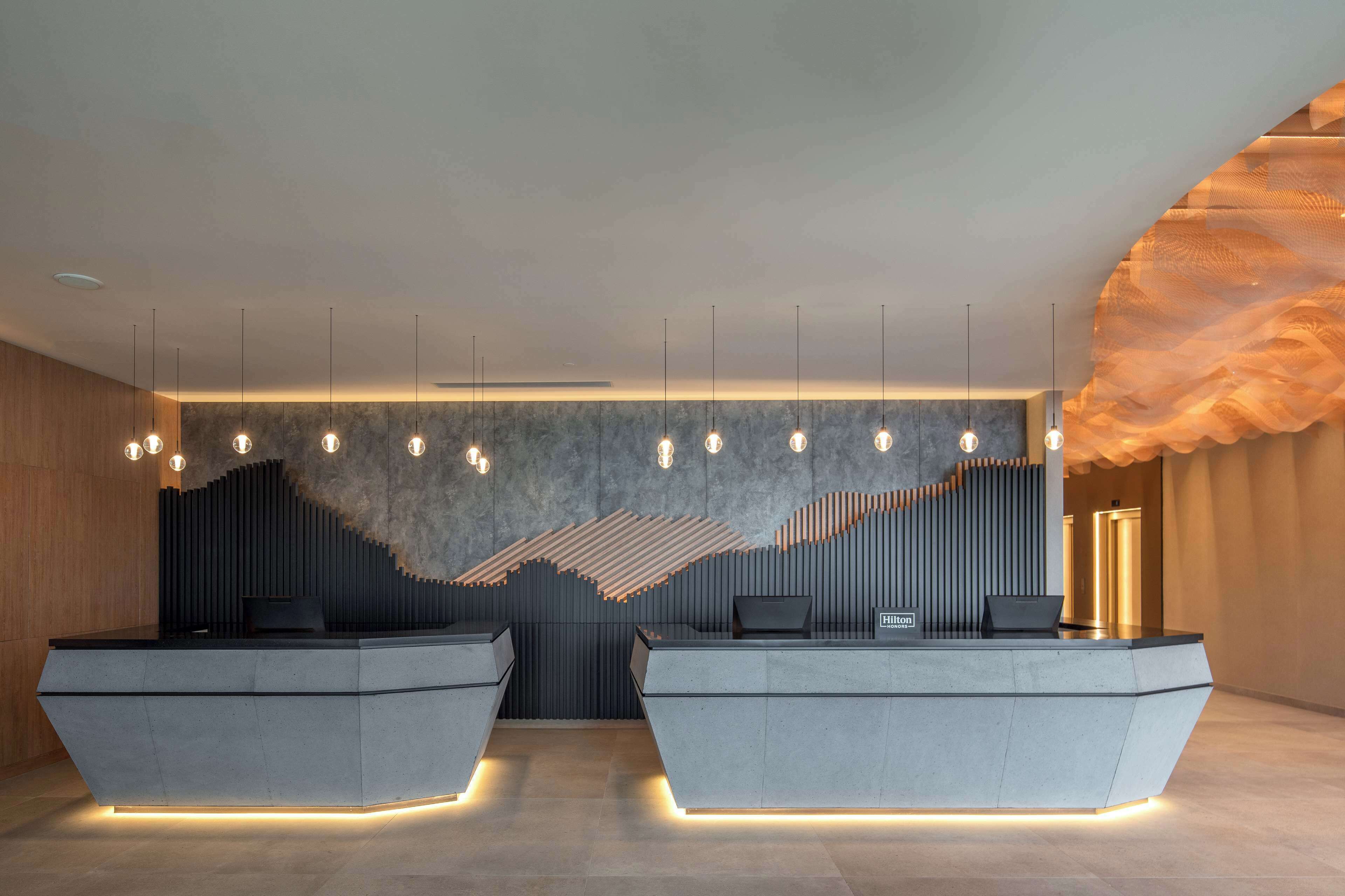 A modern reception area with two reception desks, a unique textured wall design, and pendant lighting.