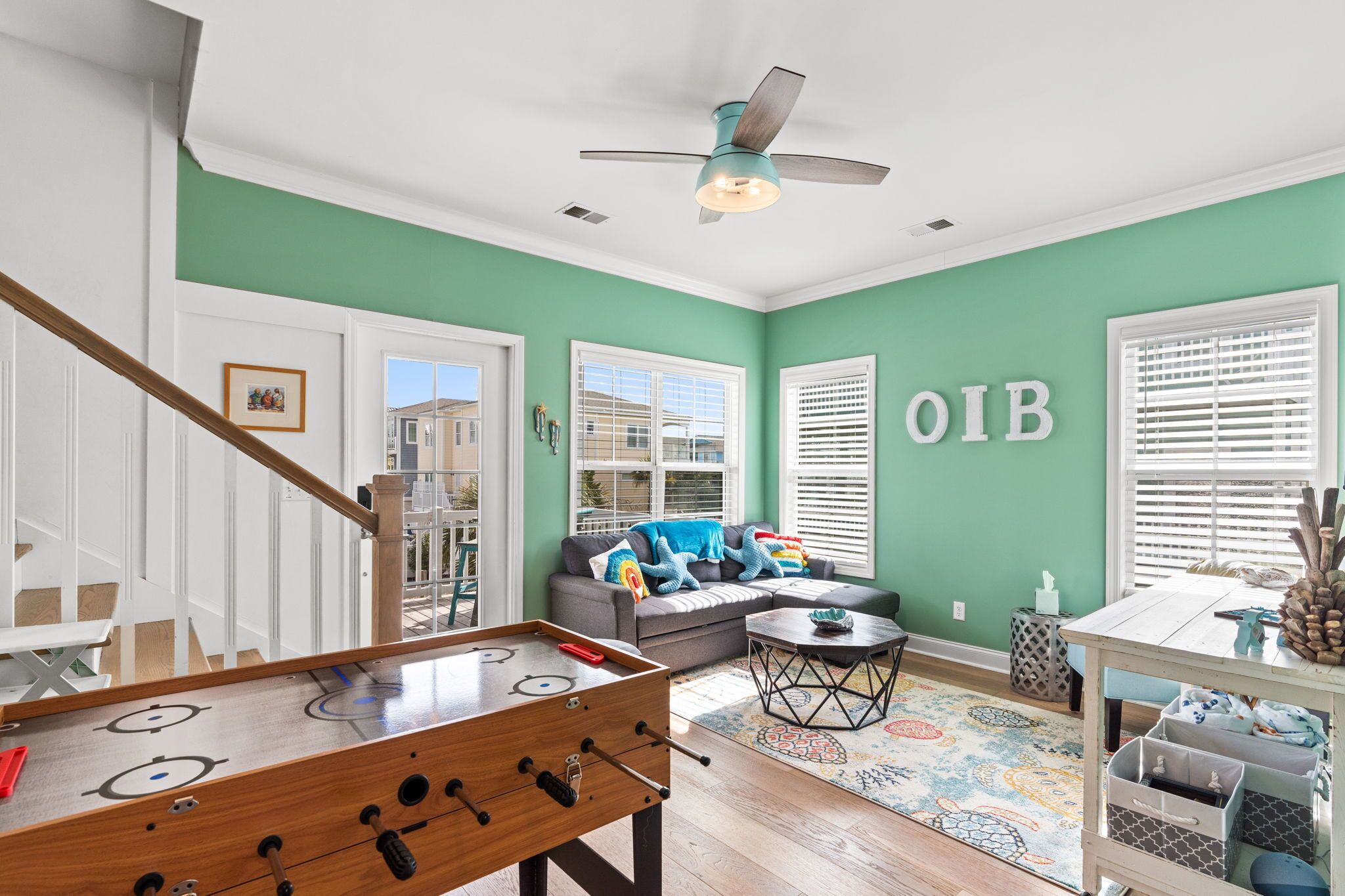A living room with a foosball table, a sofa, and a ceiling fan.