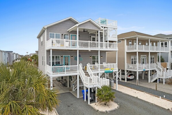 A beachfront hotel with multiple balconies, a covered outdoor seating area, and a small pool. - Rainbow Skies- 5 bedroom, 4 bath w/private pool, OIB resort & steps to the beach (Ocean Isle Beach)