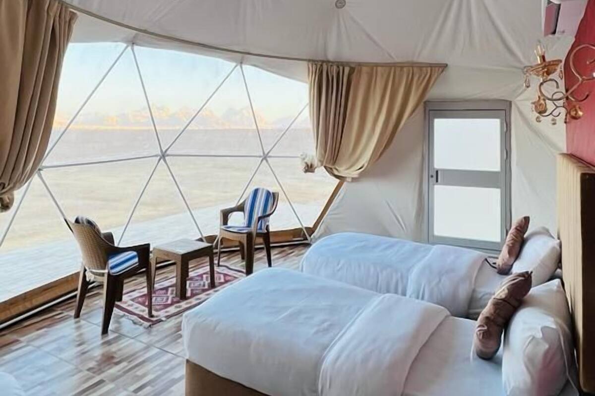 A tented room with a bed, a chair, and a table.