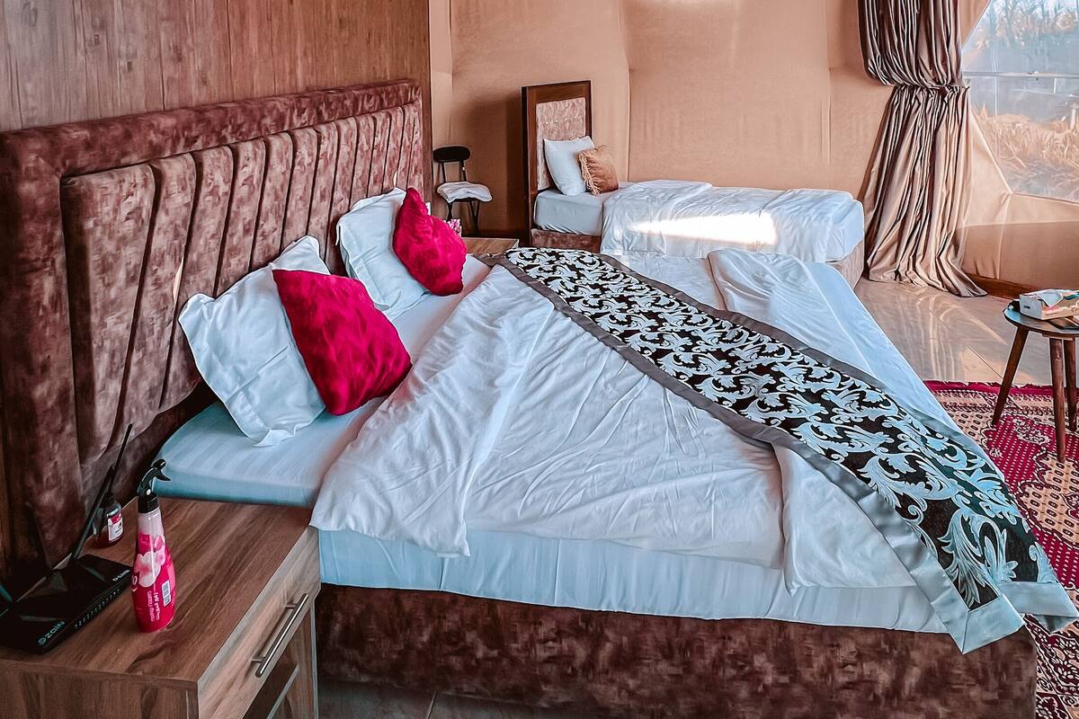 A spacious bedroom with a large bed, wooden headboard, and a modern air conditioning unit.
