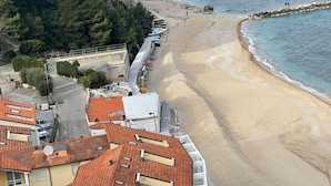 A coastal hotel with a beach view, a rocky shoreline, and a mountainous backdrop. - B&B Villa Alma (San Costanzo)