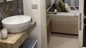 A modern bathroom with a large white sink, a wooden vanity, and a mirror with a leaf-patterned backsplash. - B&B Villa Alma (San Costanzo)