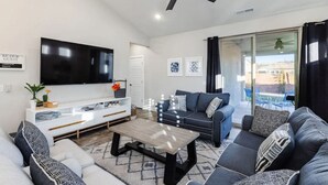 A modern living room with a flat-screen TV, a ceiling fan, a sofa set, and a coffee table. - 3 Bed Single Floor Sleeps w/pool (Washington)