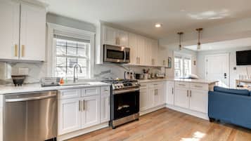 A modern kitchen with white cabinets, stainless steel appliances, and a blue sofa in the living area.