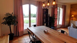 Un comedor con mesa de madera, sillas, cortinas estampadas y una lámpara colgante.