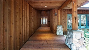 A wooden hallway with a stone pillar and a door at the end.