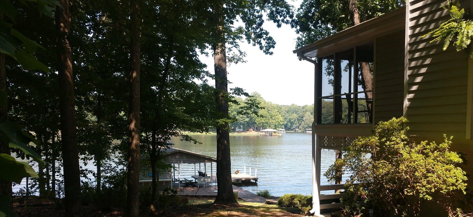 Uma cabana à beira do lago com um cais e área de estar coberta.