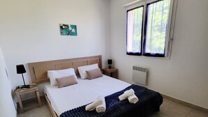 A bedroom with a bed, a nightstand, a lamp, a window, and a radiator.