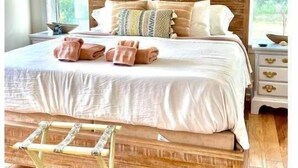 Un dormitorio con una cama de madera, ropa de cama blanca y un banco de madera.