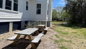 Una casa blanca con garaje y mesa de picnic en el jardín.