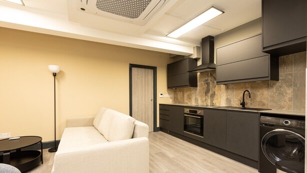 A compact kitchen with a built-in oven, a washing machine, and a sink. - Contemporary flat in the City (London)