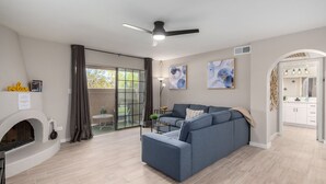 A modern living room with a blue sofa, a fireplace, and a sliding glass door leading to a balcony. - Pickleball, 3 pools & hot tubs, gated community, free parking, New listing.  (Phoenix)
