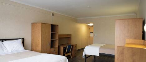 A hotel room with two beds, a desk, and a wardrobe.