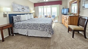 A hotel room with a bed, a dresser, a television, and a balcony with a view. - Fairways Oasis Walk-in Suite at the Fairways at Thousand Hills! Great Rates! (Branson)