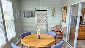 A dining area with a round wooden table, six blue upholstered chairs, a ceiling fan, and a decorative macramé wall hanging. - Fairways Oasis Walk-in Suite at the Fairways at Thousand Hills! Great Rates! (Branson)