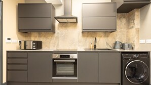 Una cuina moderna amb forn integrat, microones, rentavaixelles i rentadora.