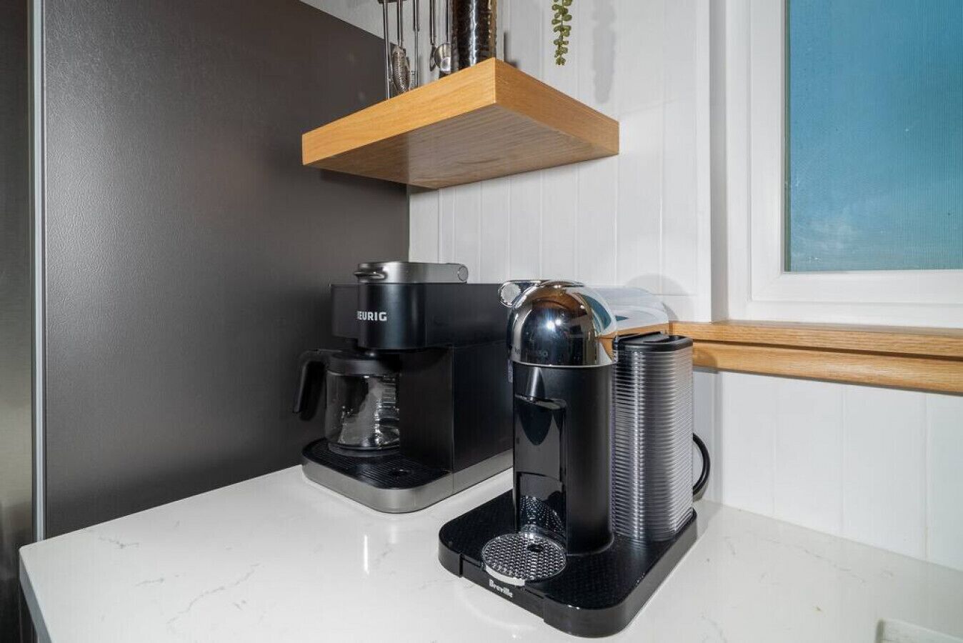 A coffee maker, a water dispenser, and a coffee pot on a white countertop.