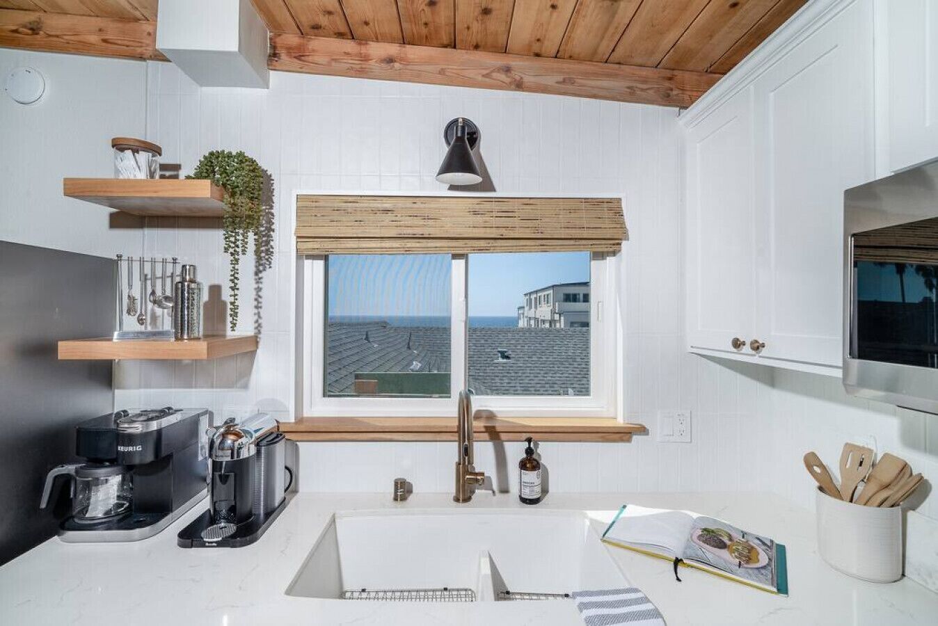 Een moderne keuken met uitzicht door het raam, een koffieapparaat en houten planken.