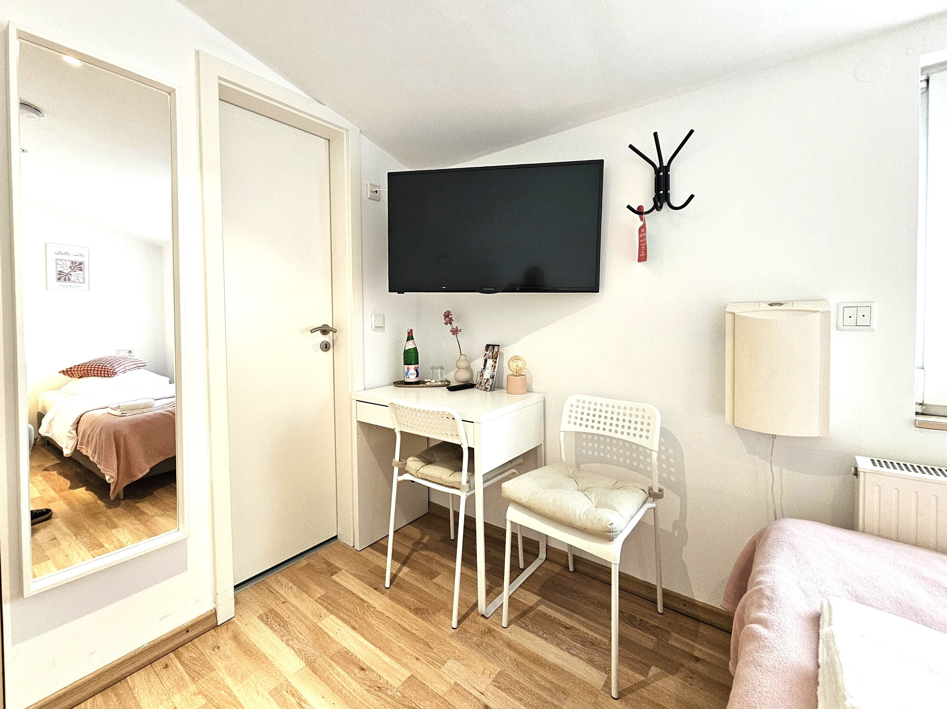 Une chambre à coucher comprenant un lit, un bureau avec une chaise, un téléviseur fixé au mur et un radiateur.