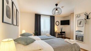 Habitación de hotel con dos camas, un escritorio, una silla, un televisor y un espejo.