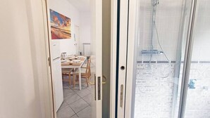 Une pièce dotée d’une porte vitrée donnant sur un espace de douche, avec un mur carrelé et une fenêtre.