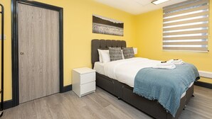 A bedroom with a bed, bedside table, and a window with blinds. - Ideally located cosy flat (London)