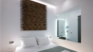 A modern hotel room with a neatly made bed, a large mirror, and a bathroom visible in the reflection. - Hyades - Downtown Suites No 3 , Mykonos Town (Mykonos, Cyclades)